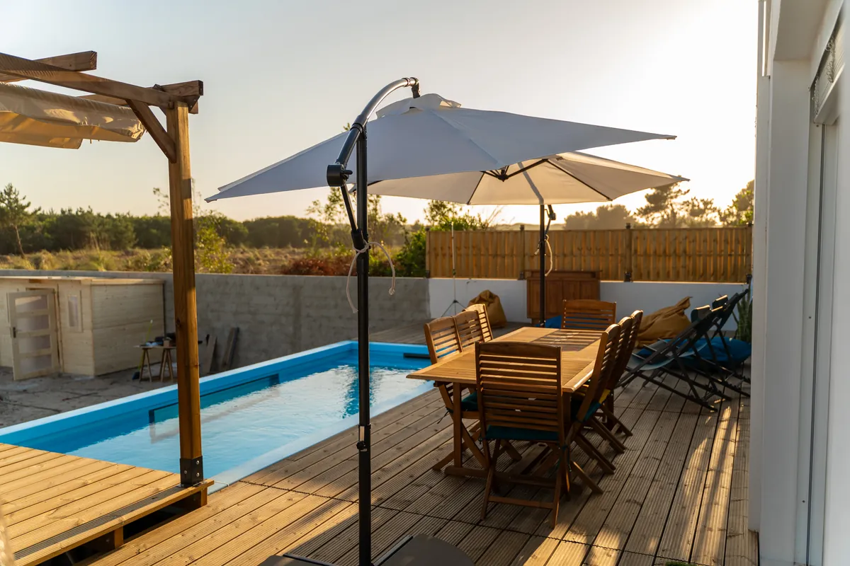Piscina e mesa de exterior no deck da Casa Aveiro ao fim da tarde