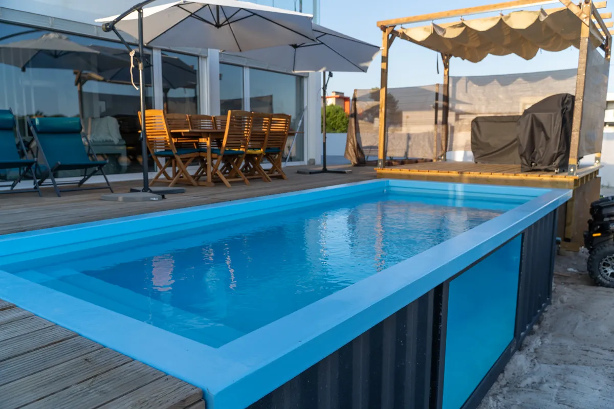 Água azul e bordadura da piscina em contentor junto ao deck da Casa Aveiro