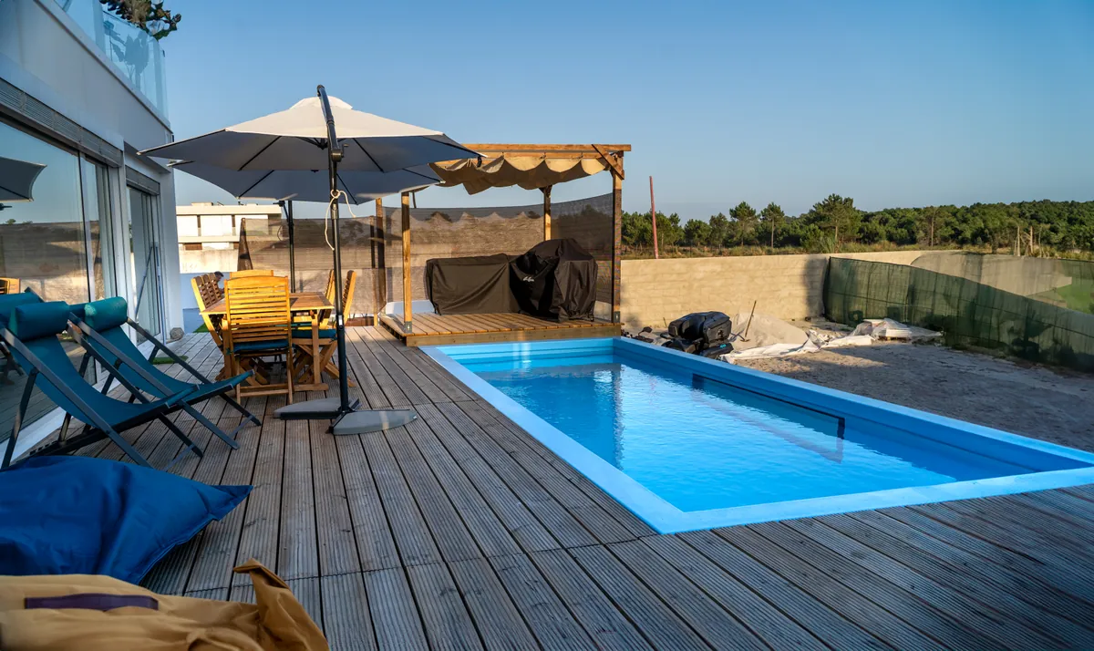 Piscina da Casa Aveiro integrada no deck de madeira, com espreguiçadeiras e zona de estar