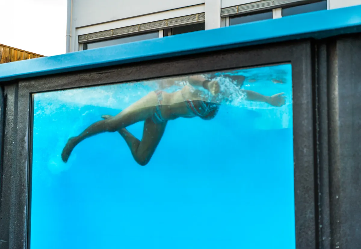 Nadador visto através da janela panorâmica da piscina da Casa Aveiro