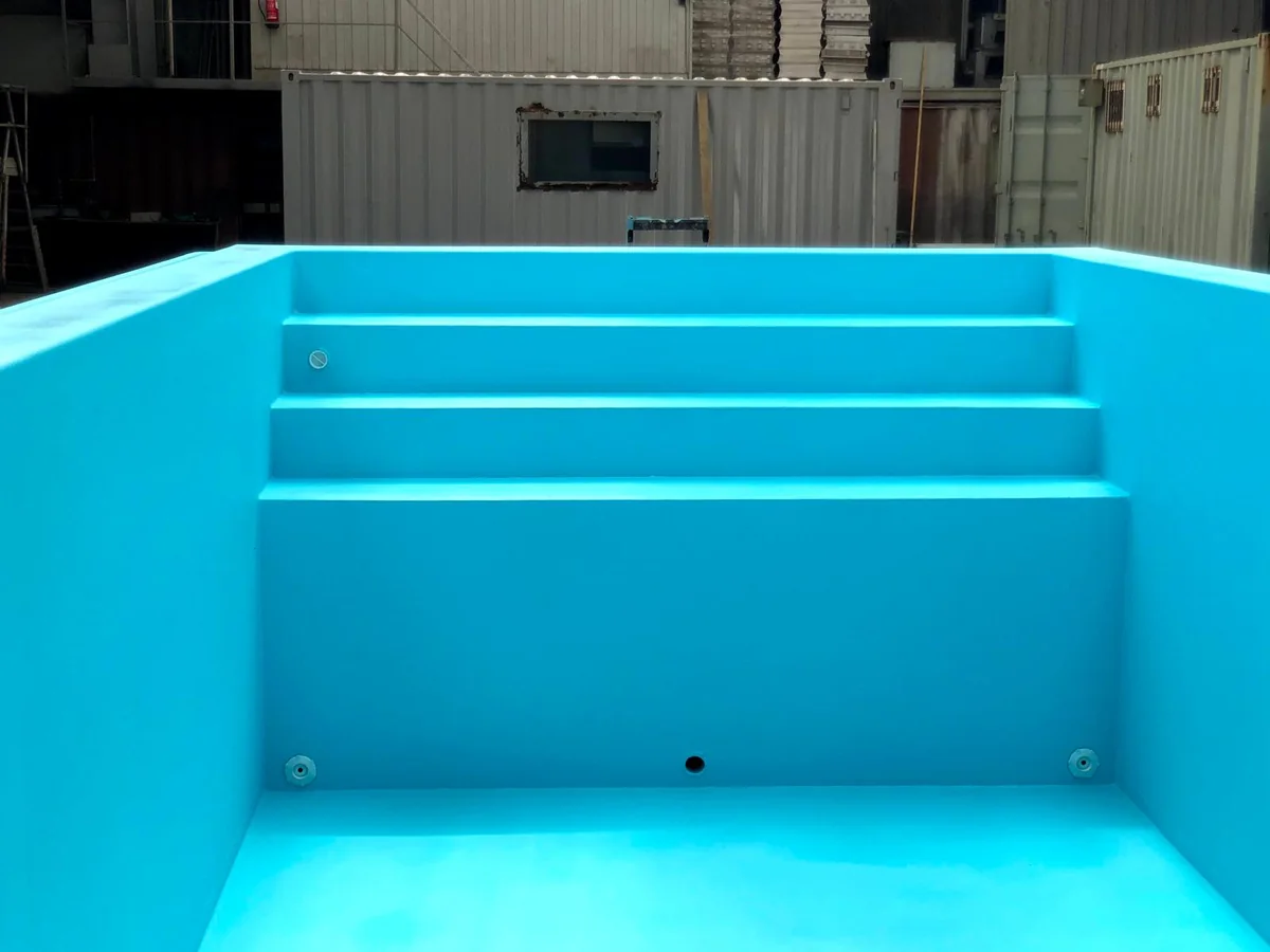 Escadas integradas e revestimento azul no interior de uma piscina em fabrico