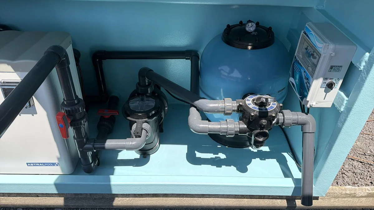 Bomba, filtro e tubagens instalados no compartimento técnico da piscina